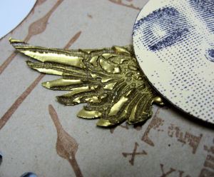 wing covered in gold embossing powder, heated, them pressed with stamp.